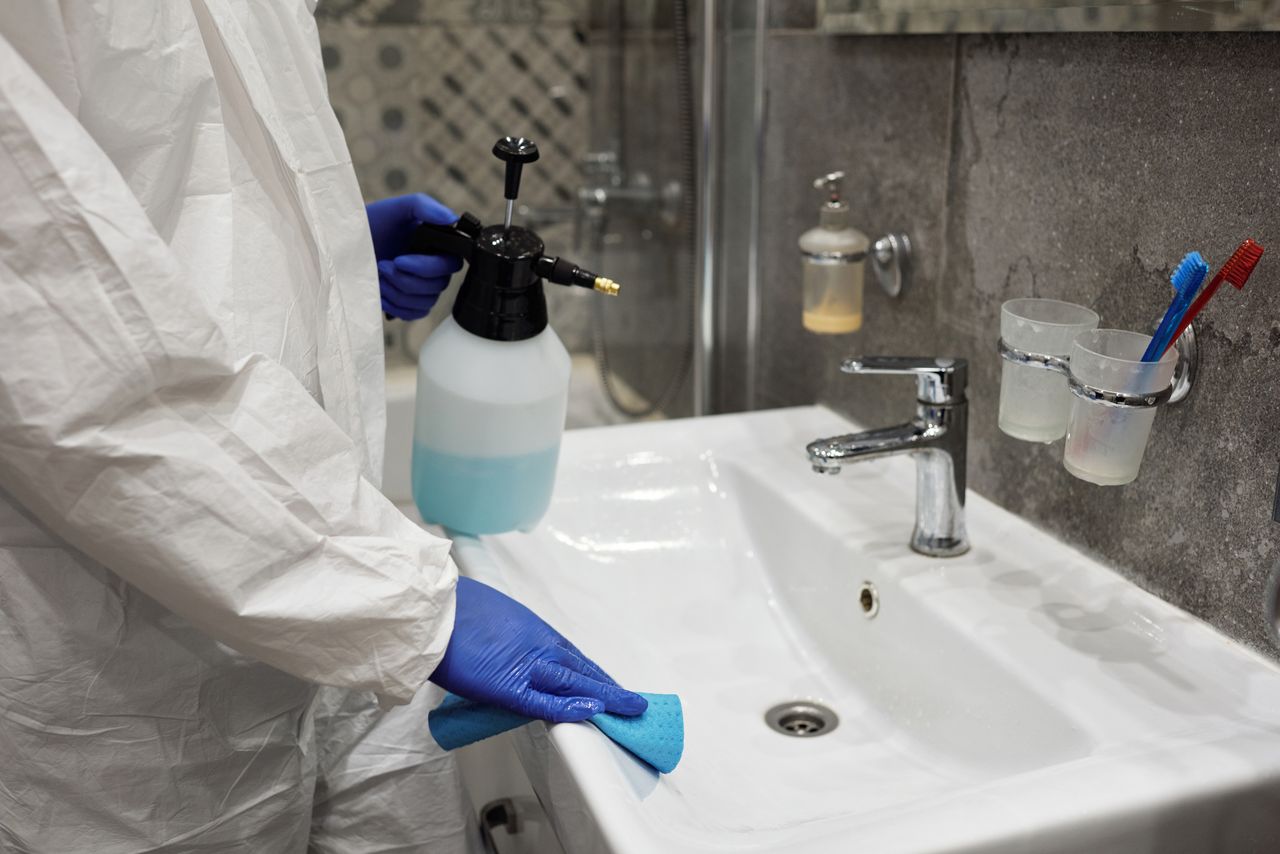 services-02 Une personne désinfecte le lavabo d’une salle de bains à l’aide d’un vaporisateur, afin de garantir l’hygiène.