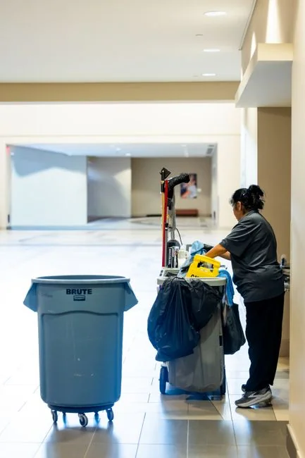 Person in full protective suit cleaning a floor, showcasing safety measures.